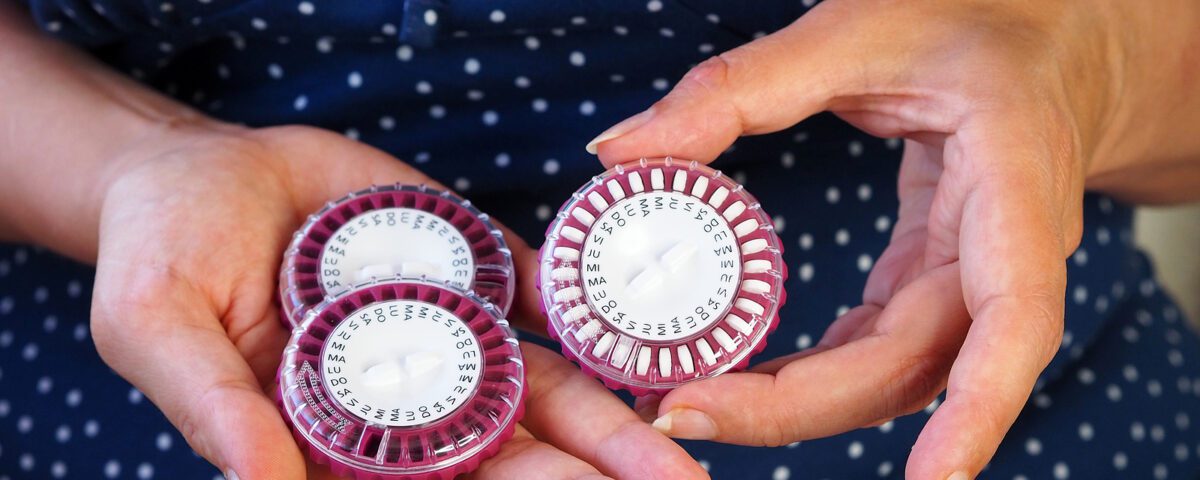 A Woman Holds Several Packs Of Hormonal Pills In Her Hands. Roun