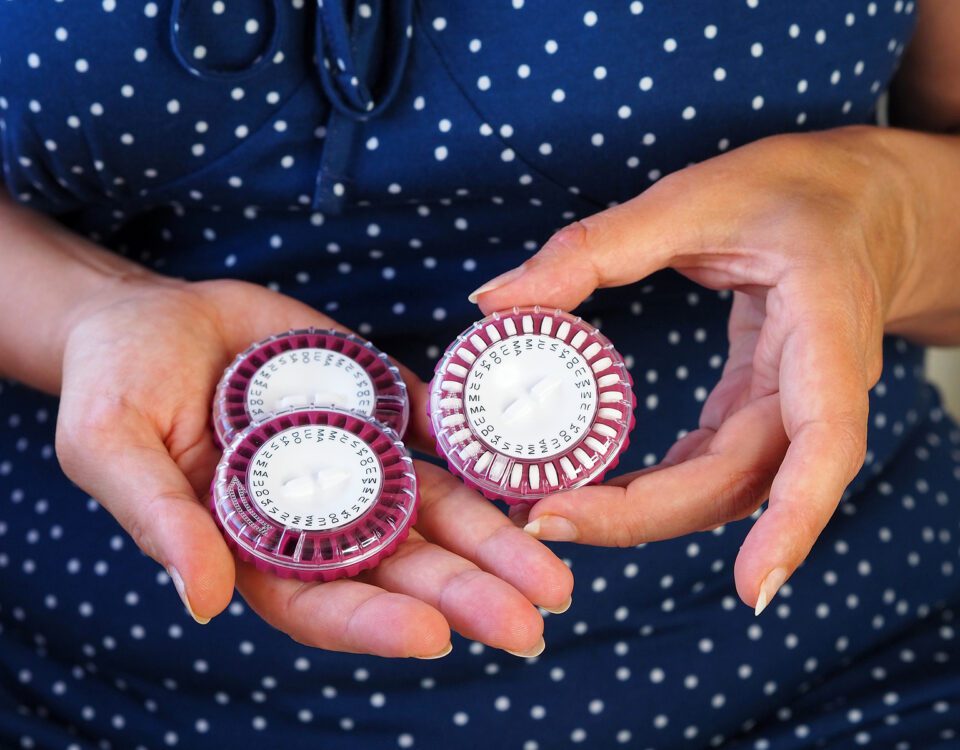 A Woman Holds Several Packs Of Hormonal Pills In Her Hands. Roun